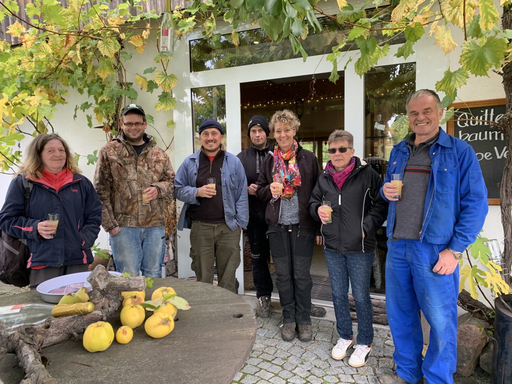 Der Winzer und seine Helfer nach der Weinlese vor dem Quittenladen mit einem Bio Federweißen in der Hand. 